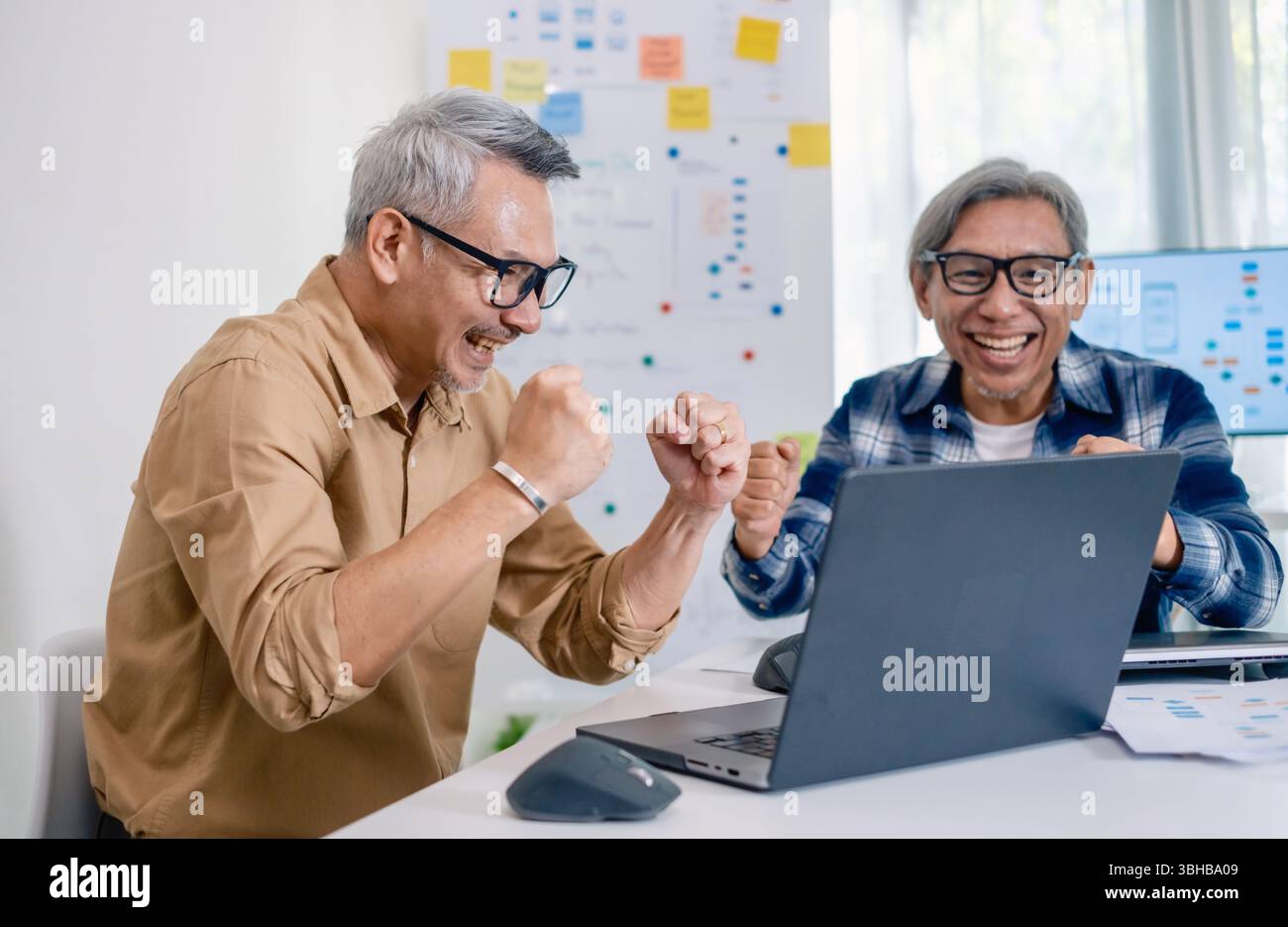 Senior developer team celebrates success in software collaboration and coding at a modern computer workstation Stock Photo