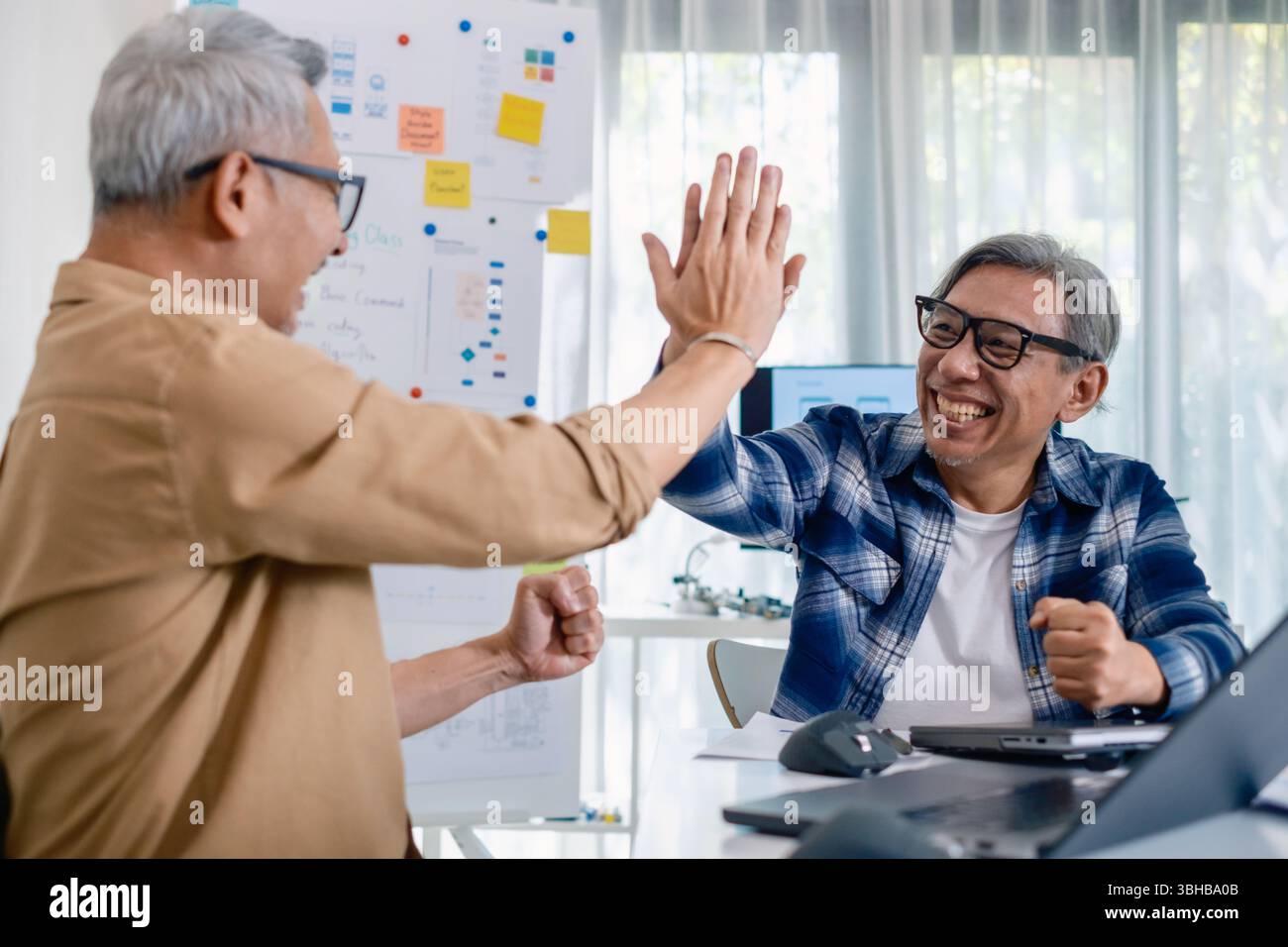 Senior developer team celebrates success in software collaboration and coding at a modern computer workstation Stock Photo