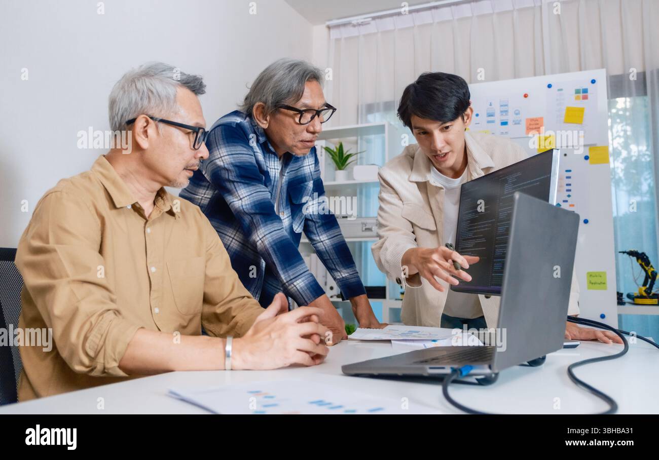 Team of developers collaborating in brainstorming and coding project at office workspace Stock Photo