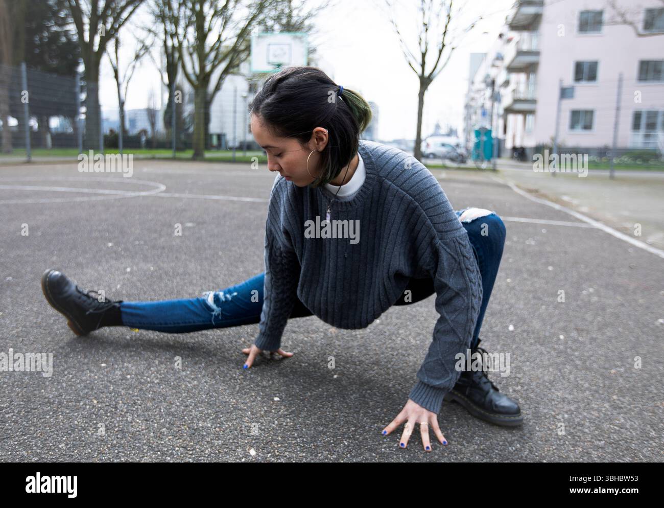 Young woman stretching her legs before street dancing practice. Stock Photo