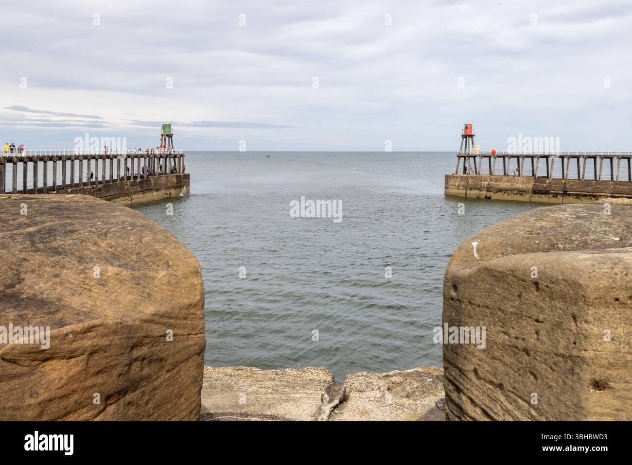 Whitby’s East and West piers lead out to the North Sea, a striking feature of this historic harbour and popular UK seaside destination. Whitby tourism Stock Photo