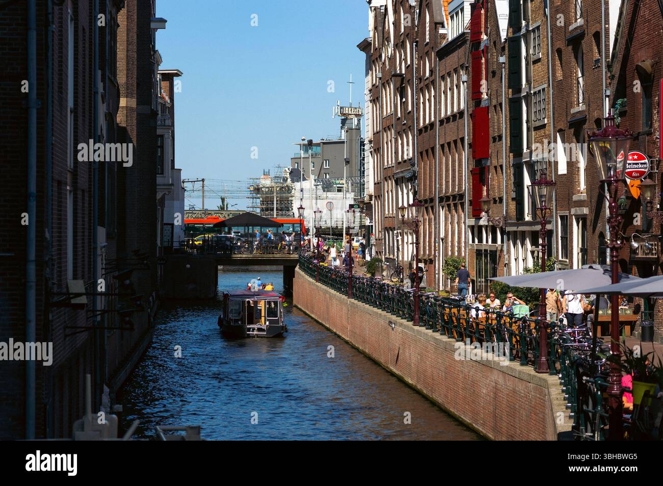 Amsterdam canal with boats, narrow buildings, and bicycles Stock Photo