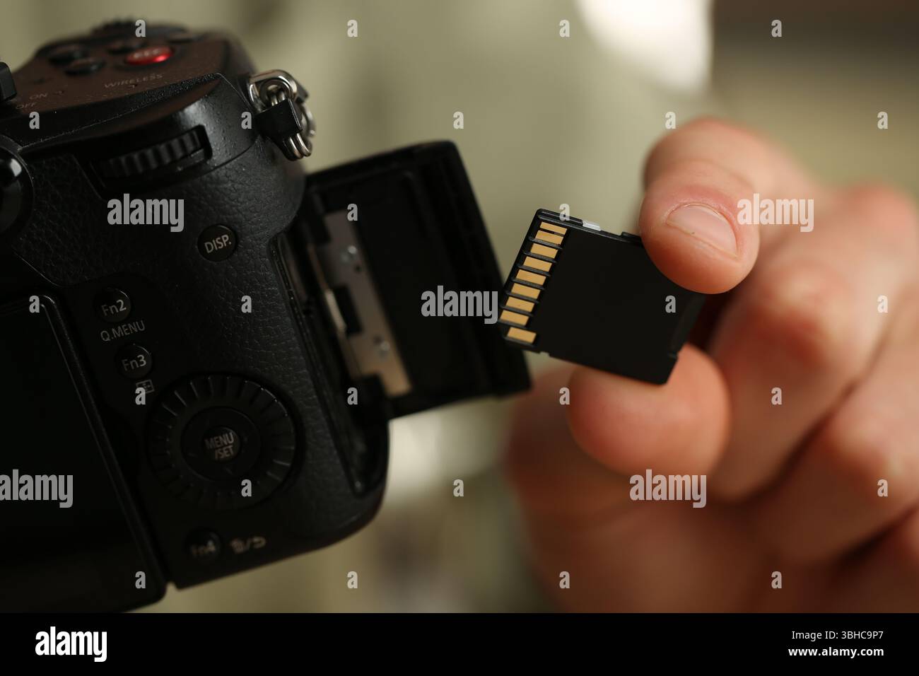 Man inserting SD memory card into photo camera, closeup Stock Photo
