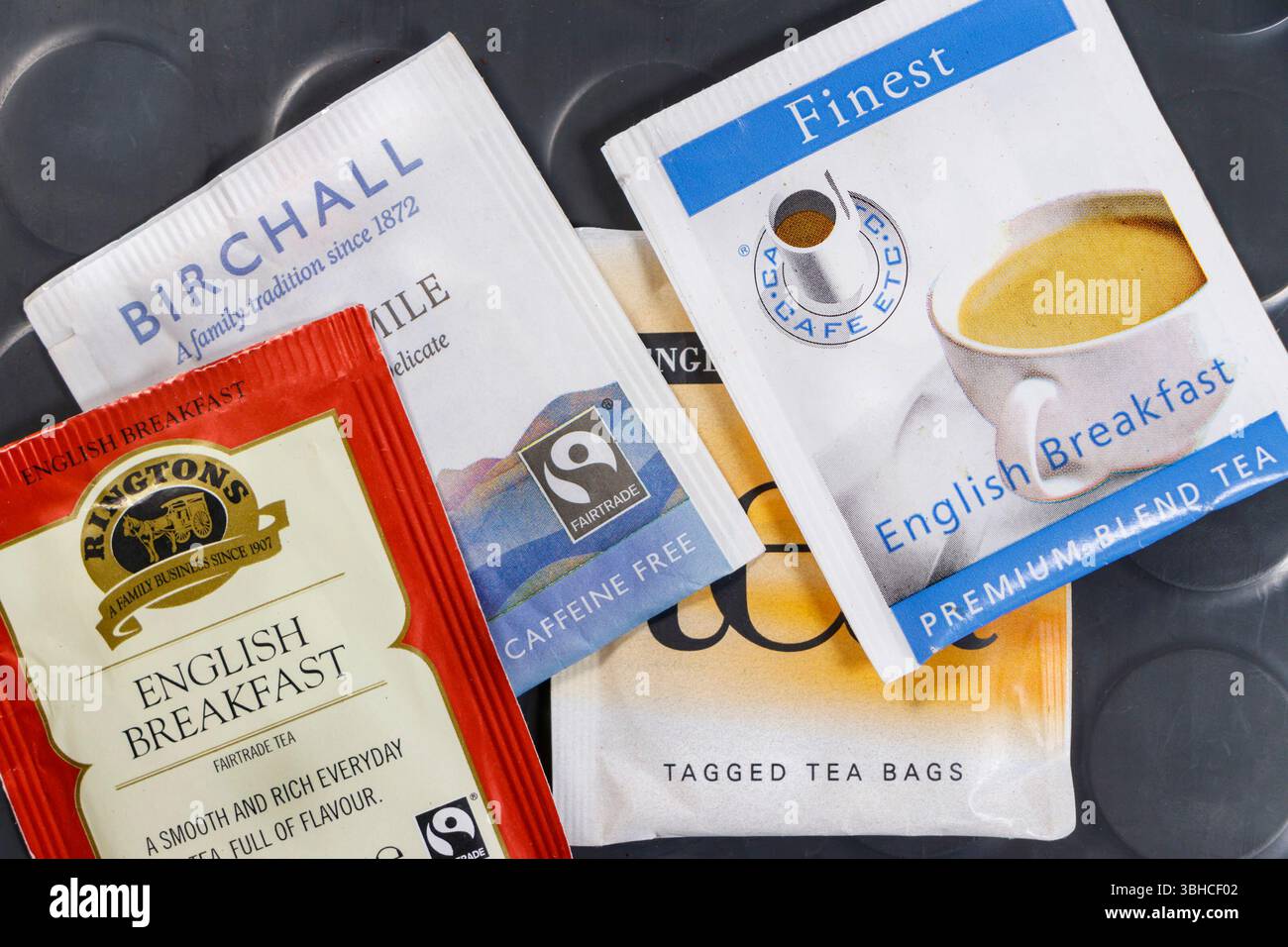 Collection of various English breakfast tea bags including Birchall, Ringtons, and Finest on a grey table. Stock Photo