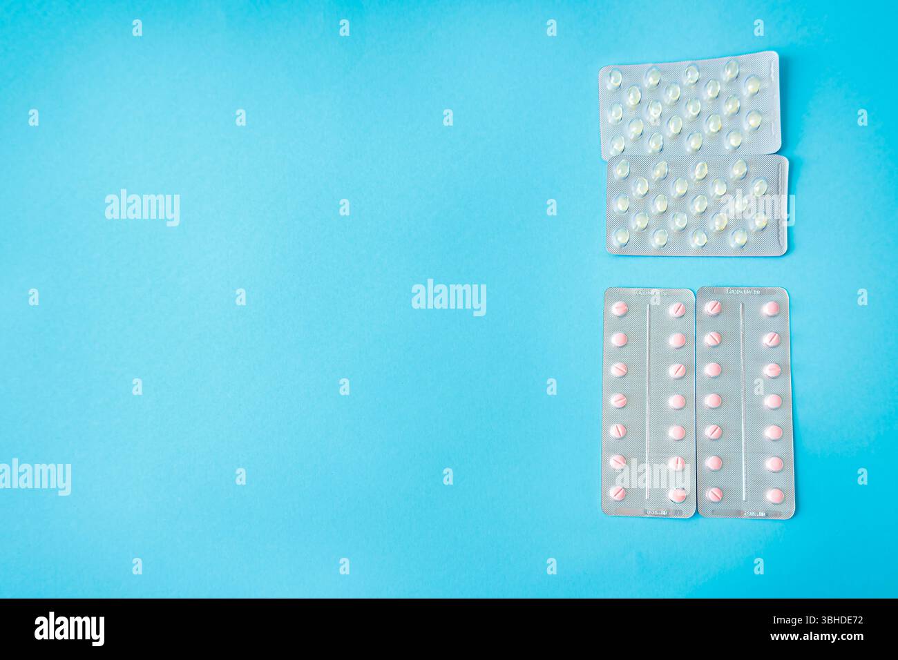 Top view of pink and white pills in blister packs on light blue ...