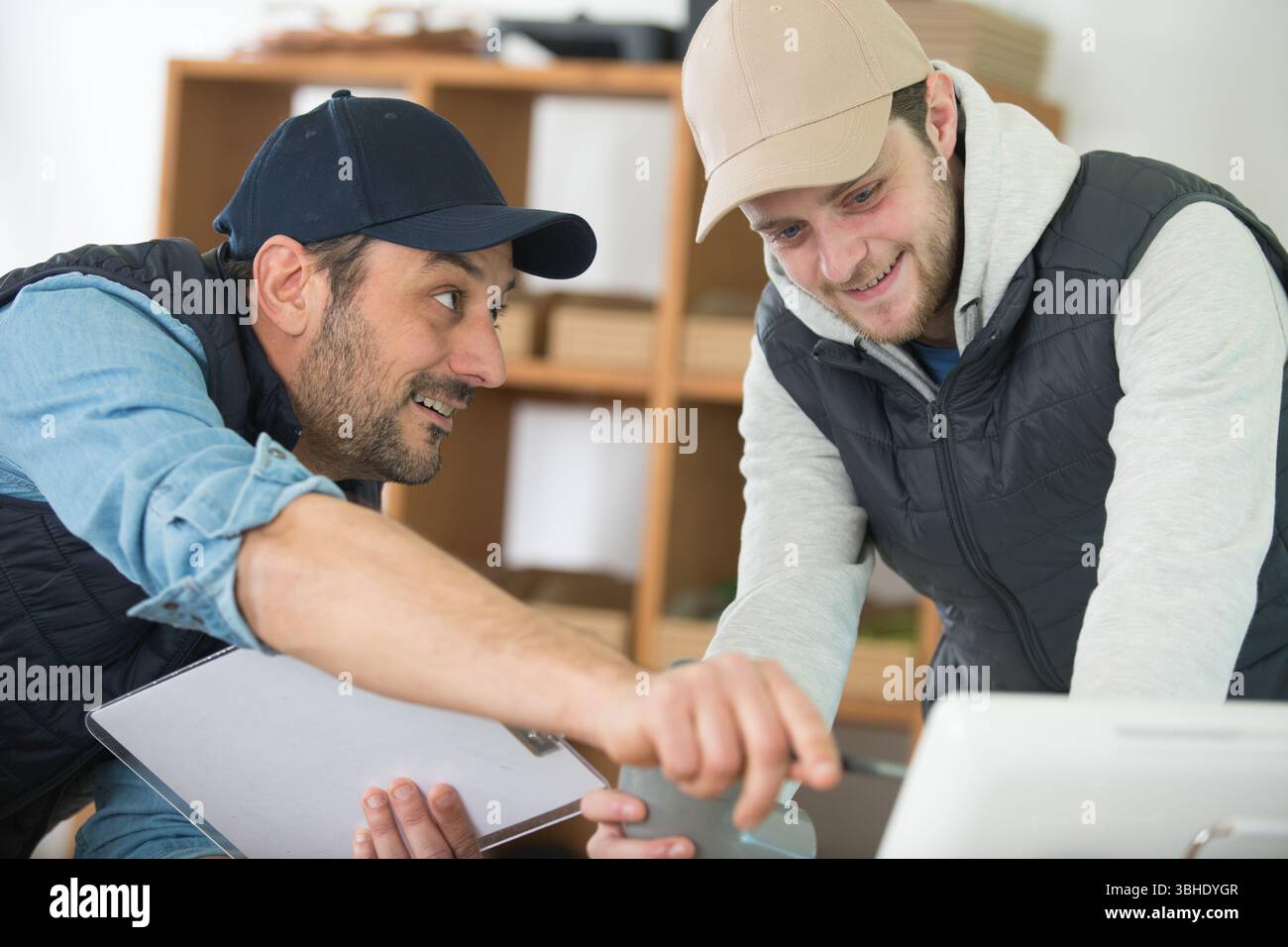 two men in workshop looking at computer screen Stock Photo
