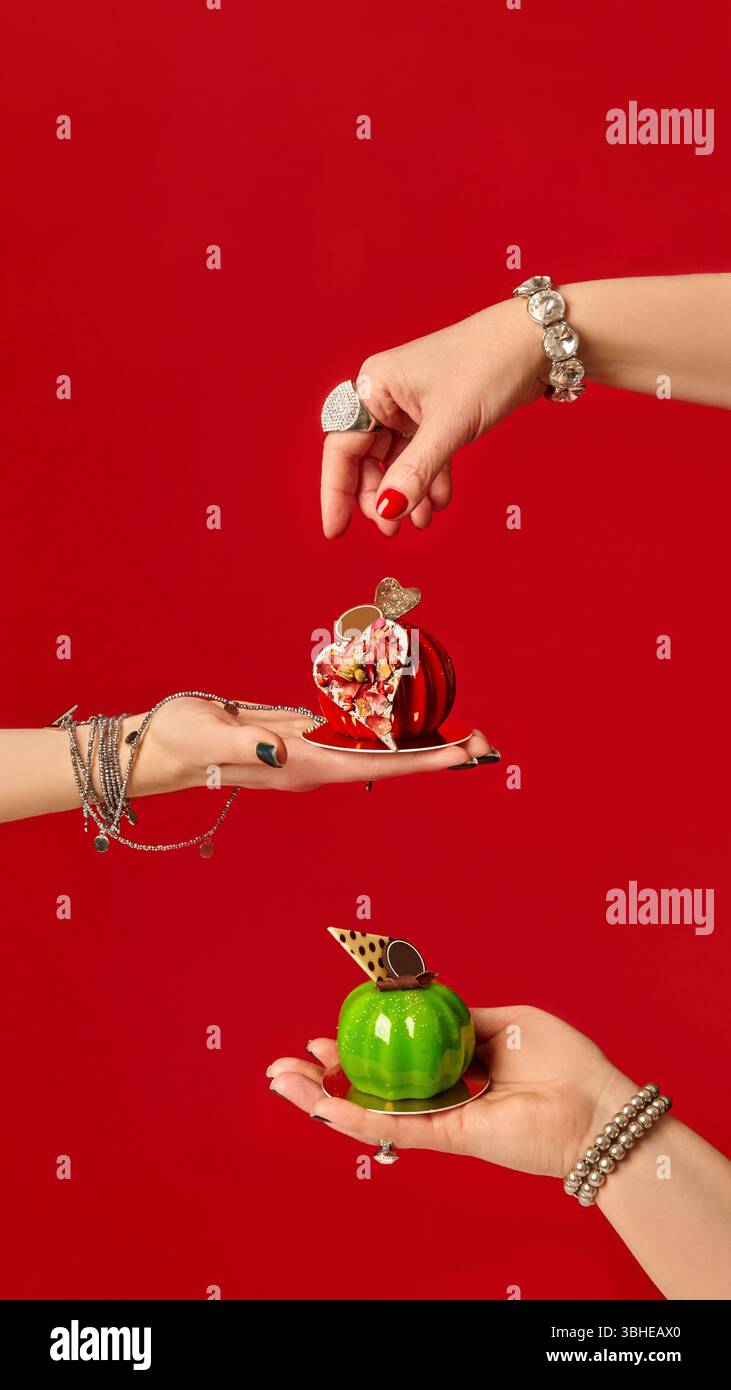 Pastry chefs holding mini apple-shaped cakes on red background Stock Photo