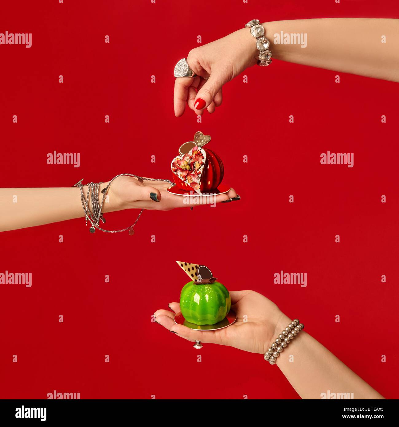 Pastry chefs holding mini apple-shaped cakes on red background Stock Photo