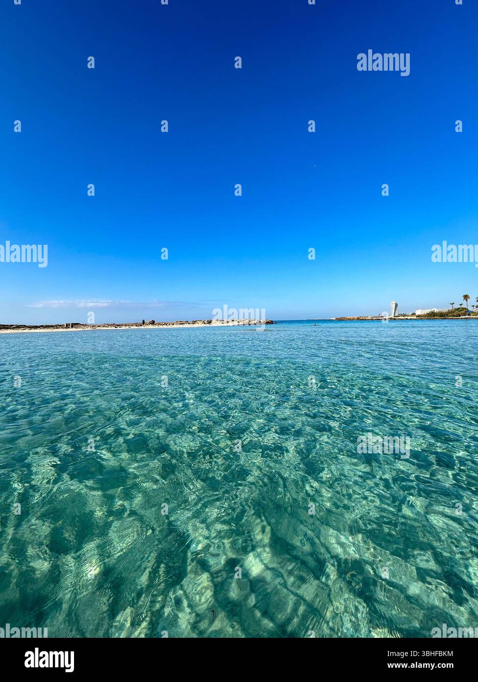 Tranquil seascape with crystal-clear shallow water and deep blue sky, perfect for travel, nature, and summer-themed projects. - Smartphone Captured Stock Image