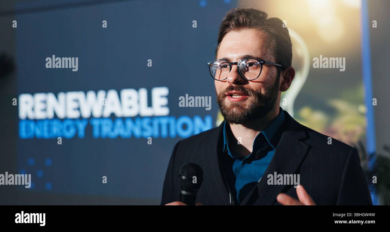 Microphone, presentation and businessman on a stage at conference for renewable energy transition. Public speaker, seminar and male environmental Stock Photo