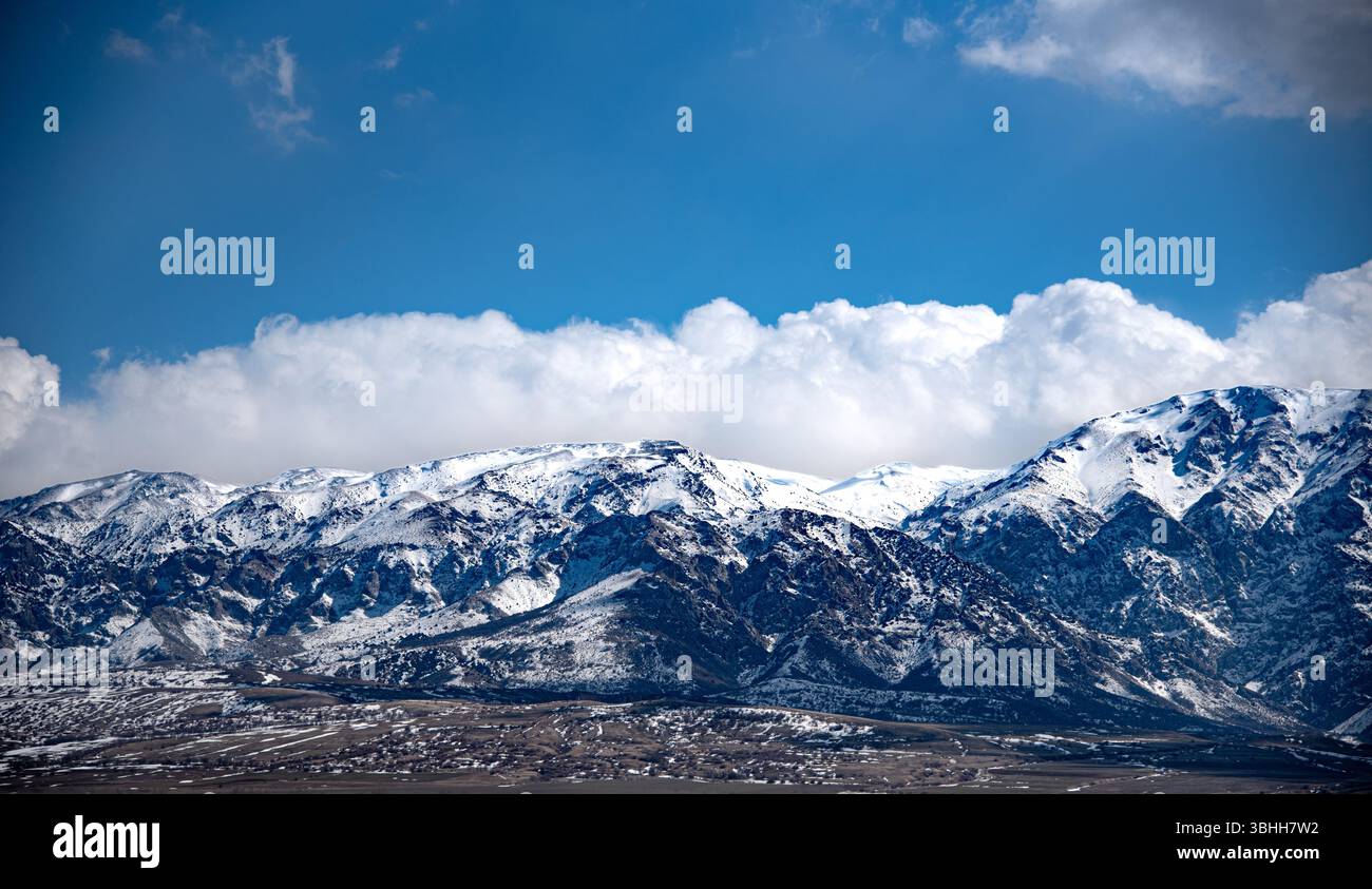 The image shows a majestic mountain range covered in snow under a ...