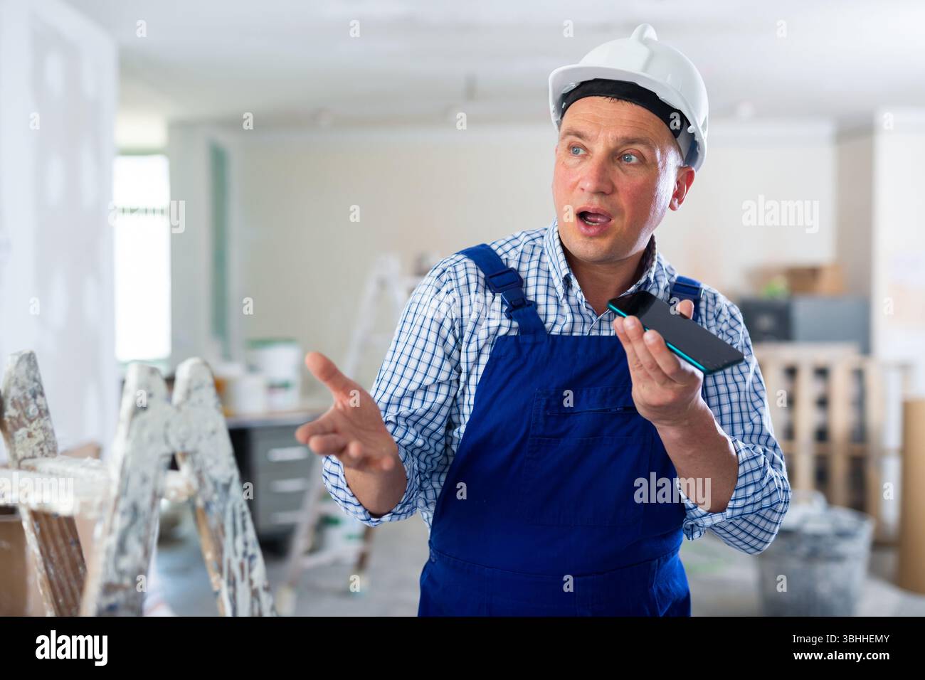 Foreman using smartphone, recording voice message Stock Photo