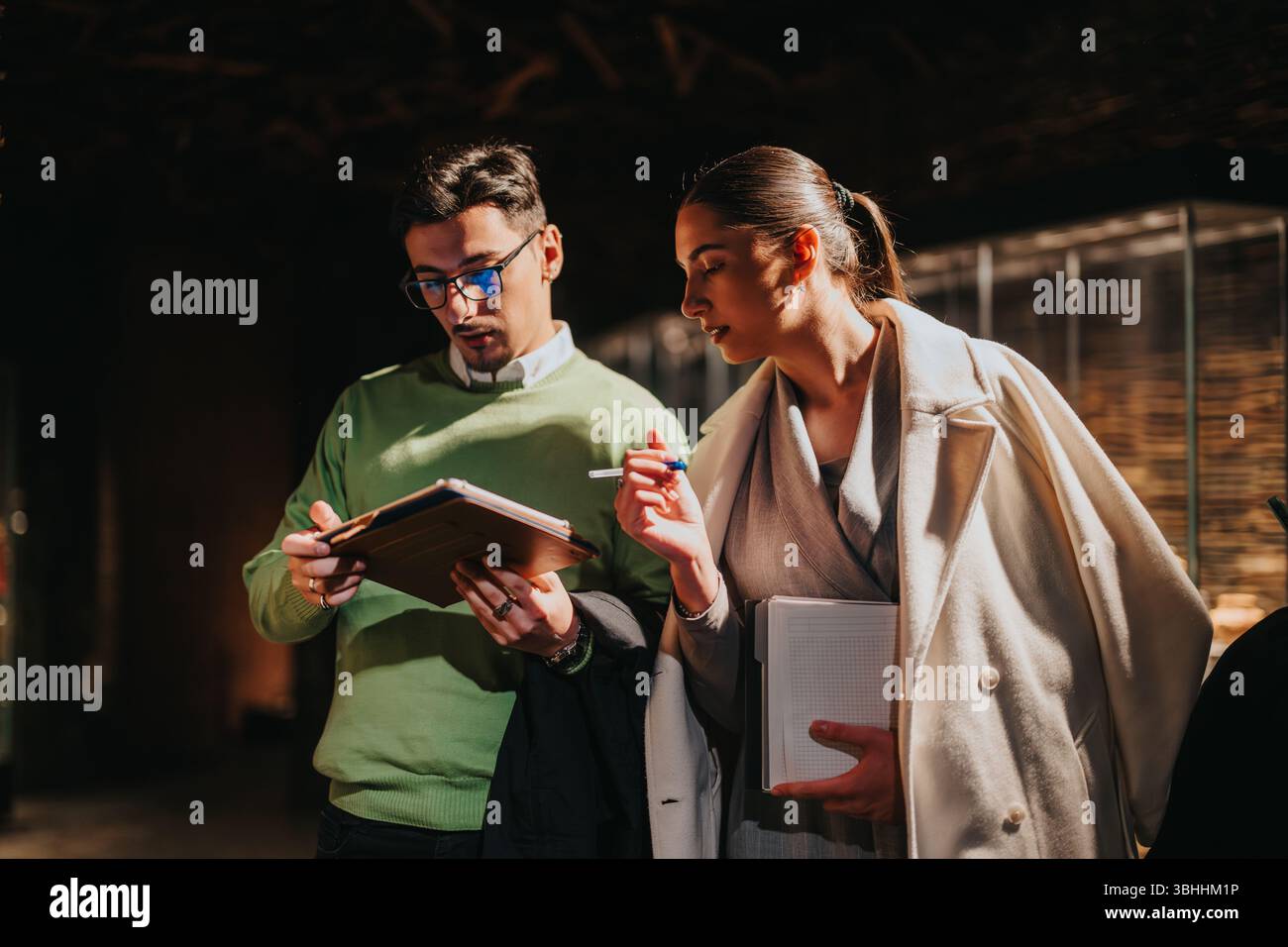 Two professionals collaborating and discussing notes inside a modern museum environment Stock Photo
