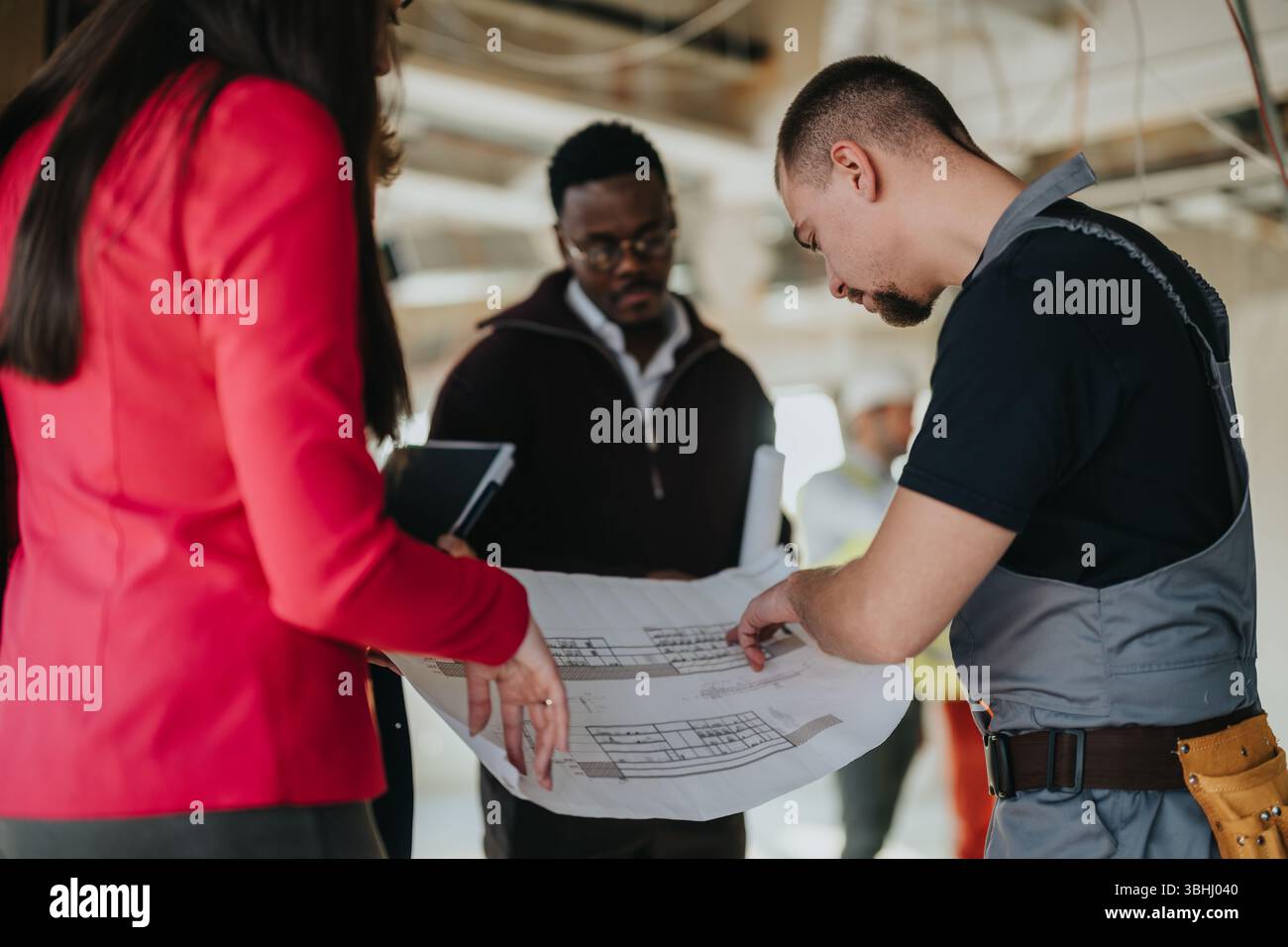 Construction professionals collaborating on a project plan in a building Stock Photo