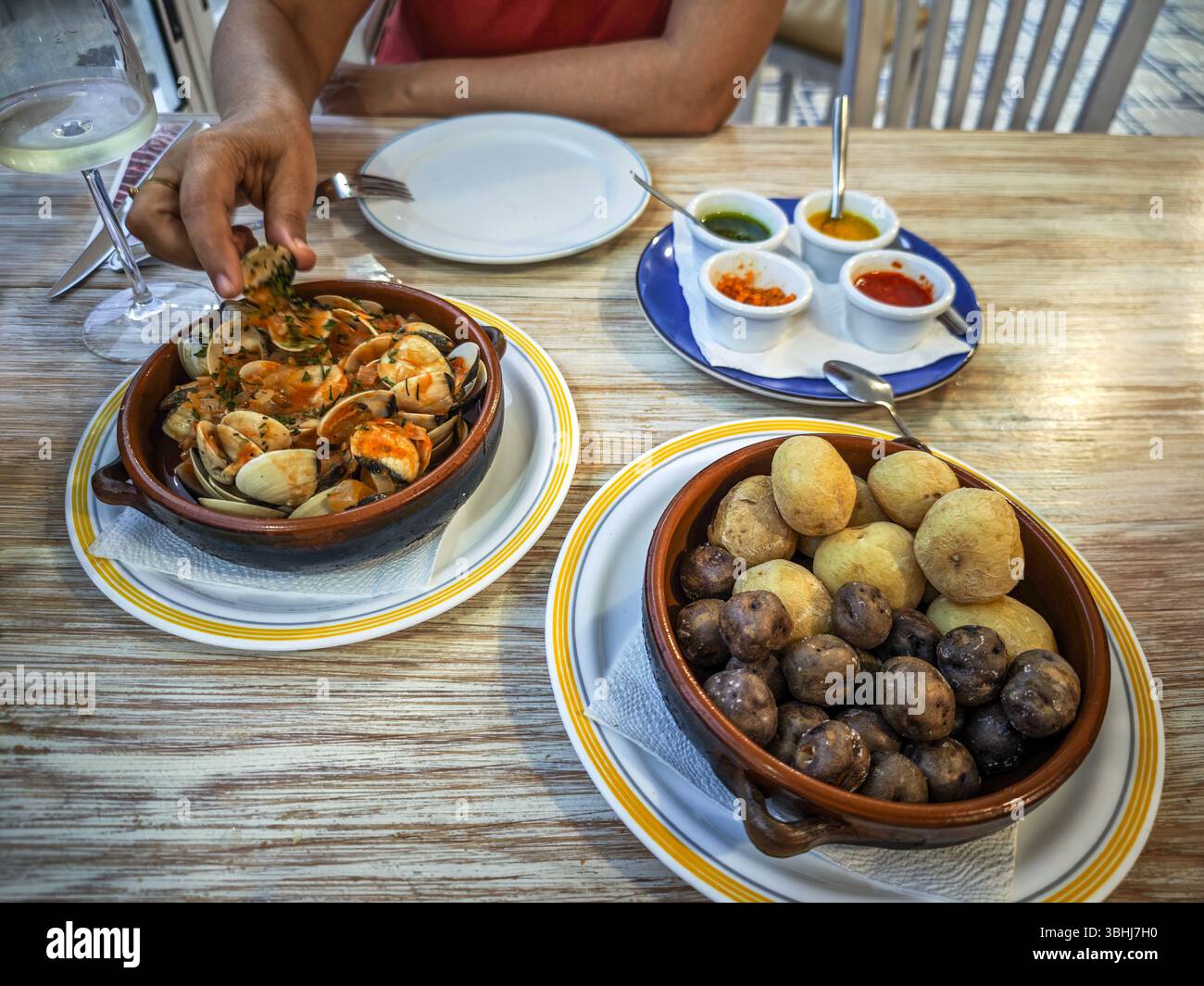 Indulging in papas arrugás with mojos and Canarian-style clams in Órzola, Lanzarote, showcasing the local flavors of the Canary Islands. Stock Photo