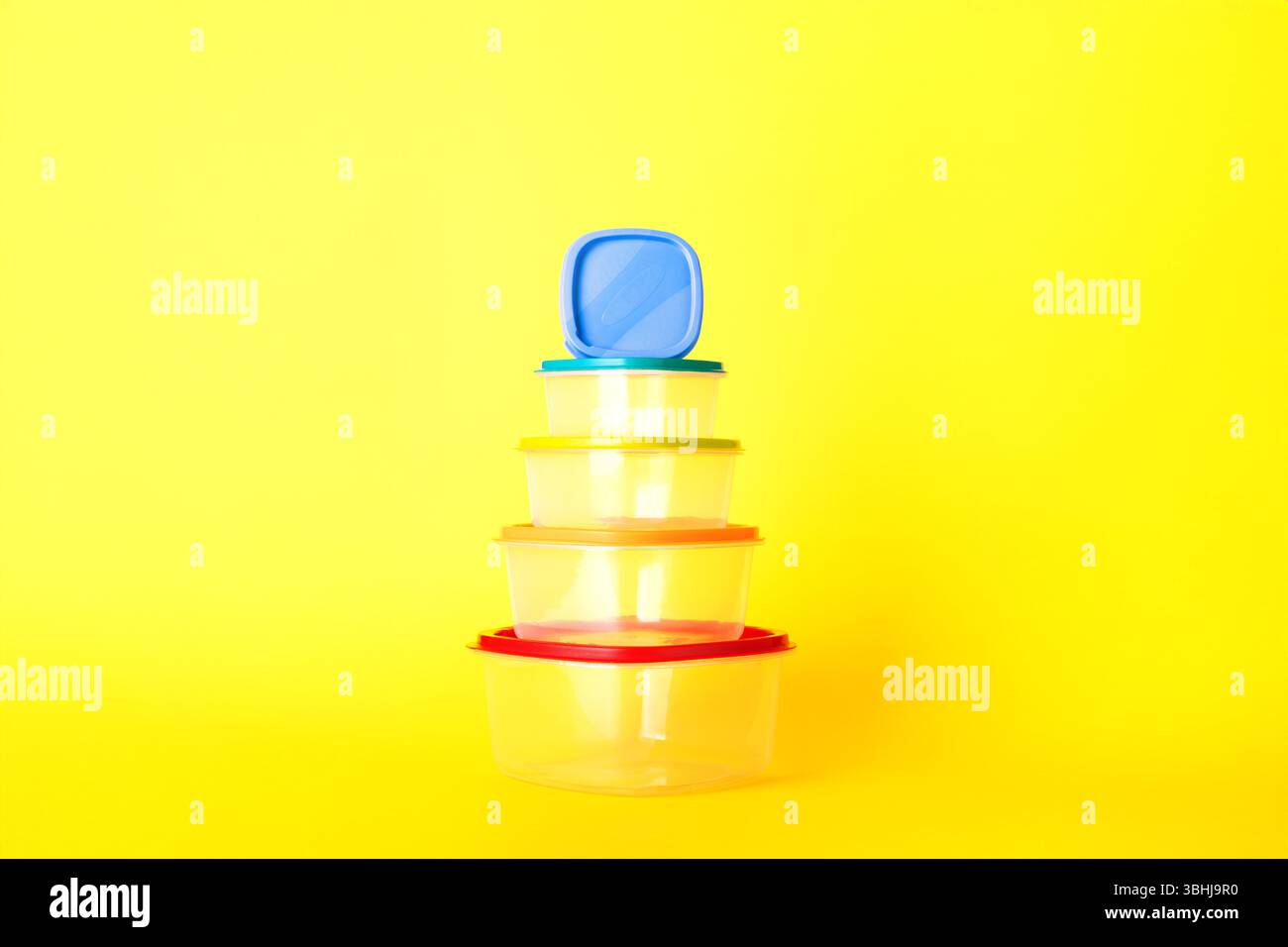 Transparent plastic containers with colorful lids stacked in a pyramid ...