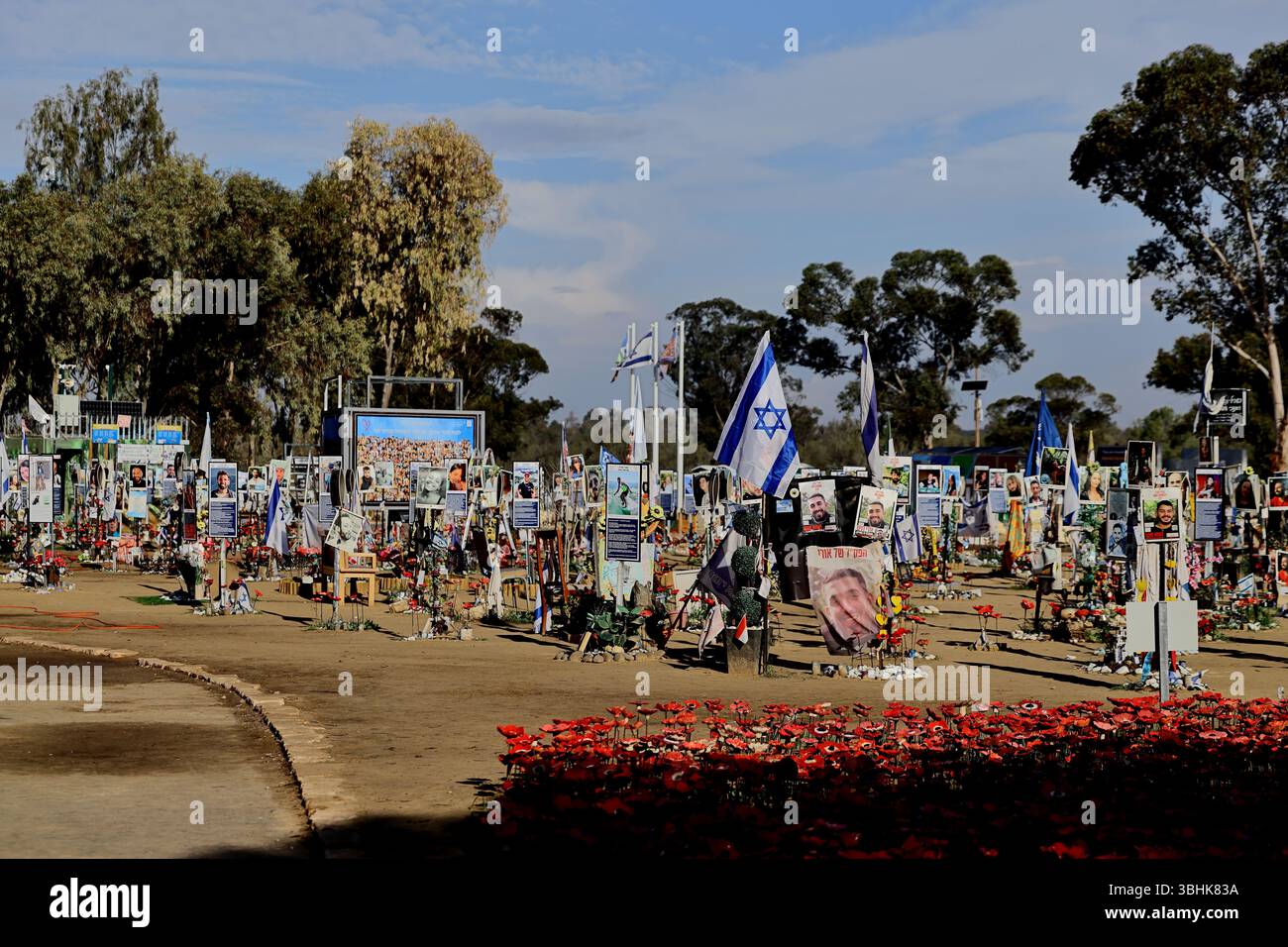 Amid rows of red ceramic poppies portrait signs and Israeli flags wave at the Re’im Forest October 7 Memorial a poignant tribute to lives lost forever Stock Photo