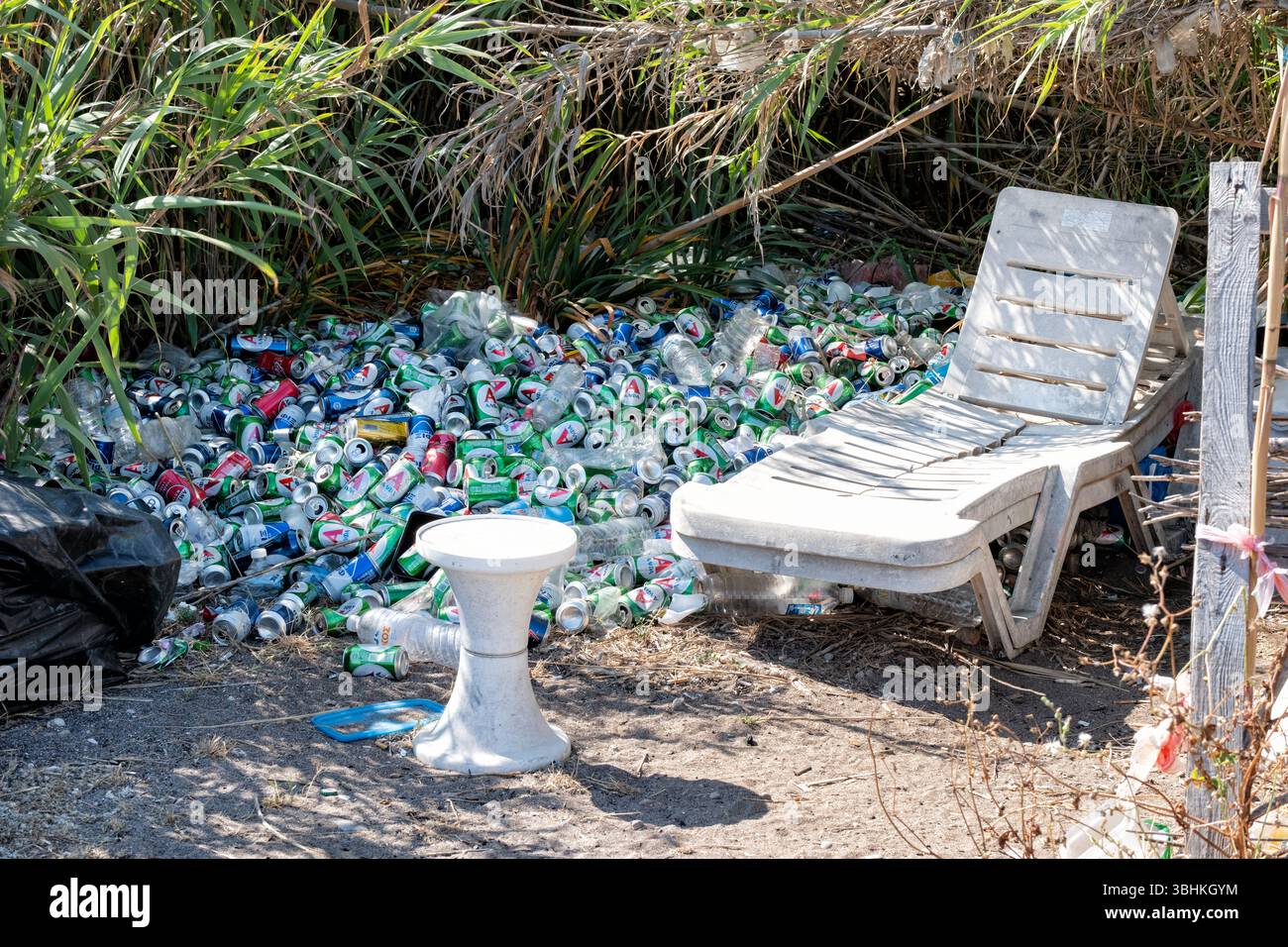 Rhodes, Greece. A collected pile of rubbish abandoned on a beach. the pile at the back of the beach includes numerous drink cans and broken furniture Stock Photo