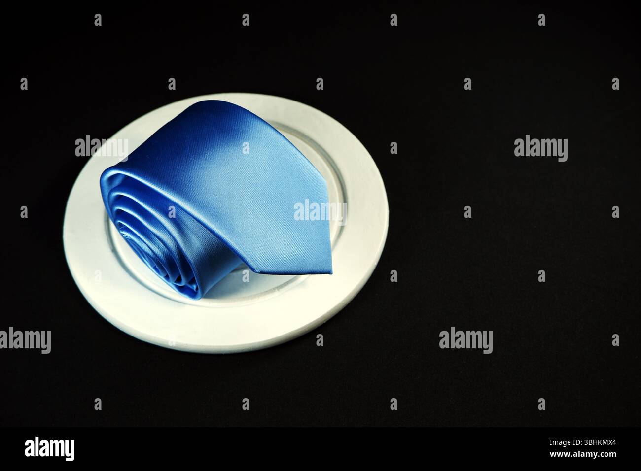 Rolled blue tie isolated on black background closeup view Stock Photo