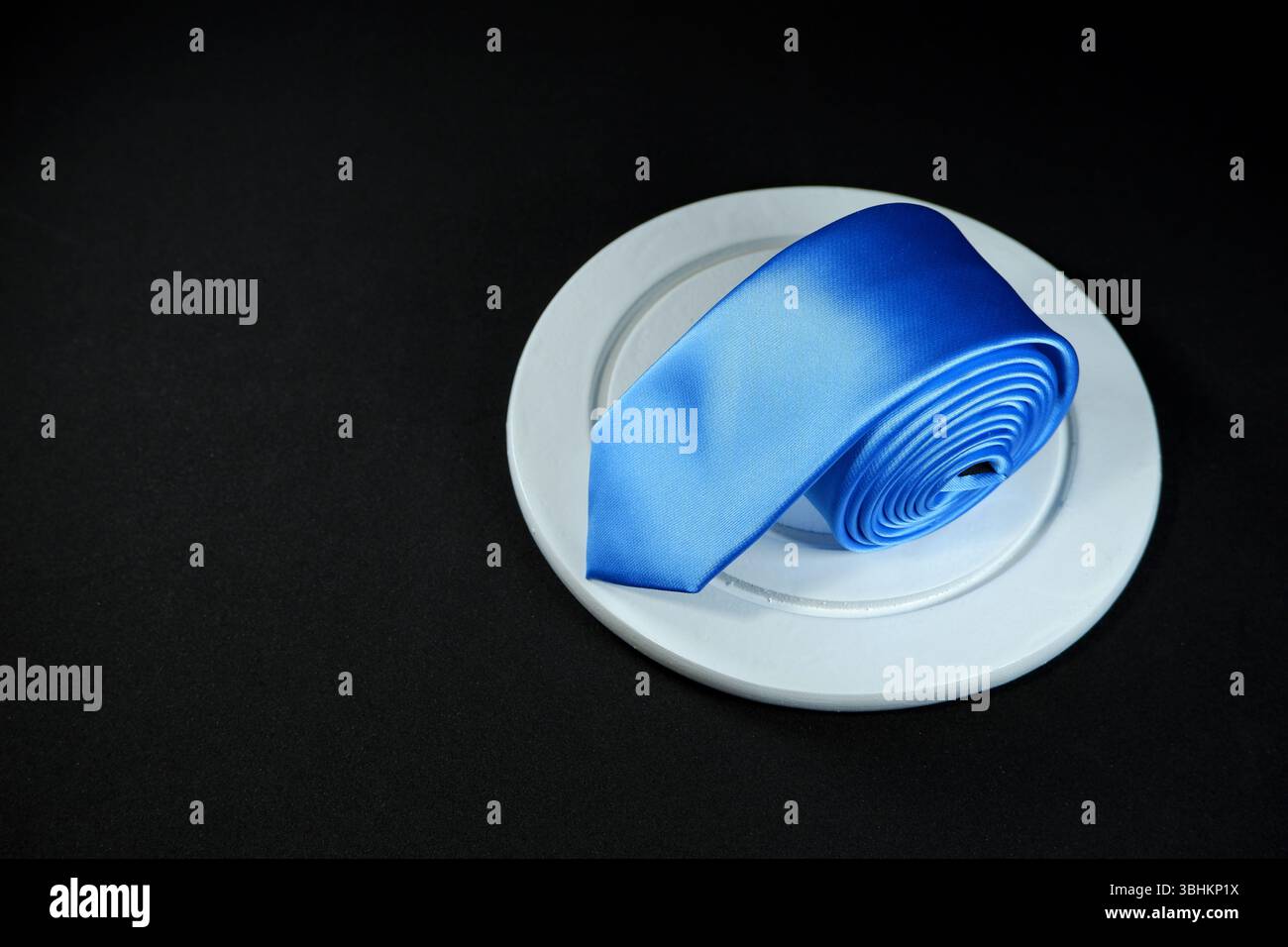 Rolled blue tie isolated on black background closeup view Stock Photo
