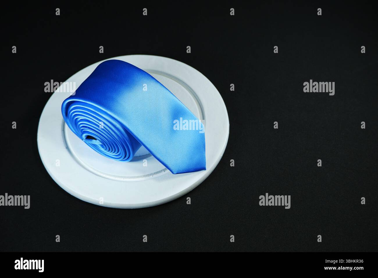 A blue tie rolled on black background with copy space Stock Photo