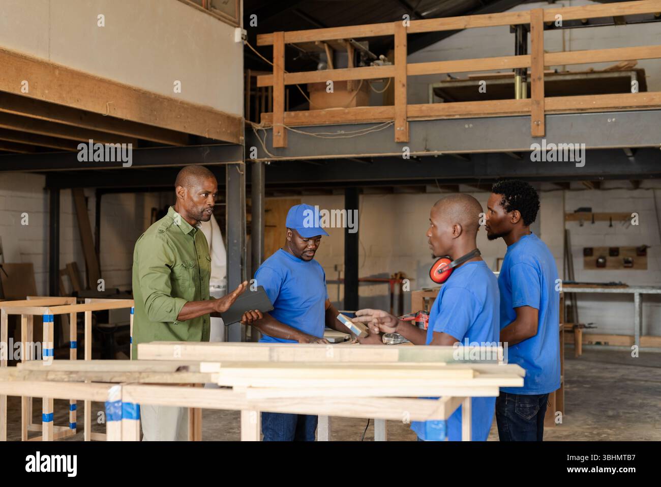 African American carpentry workers discussing measurements at shop ...