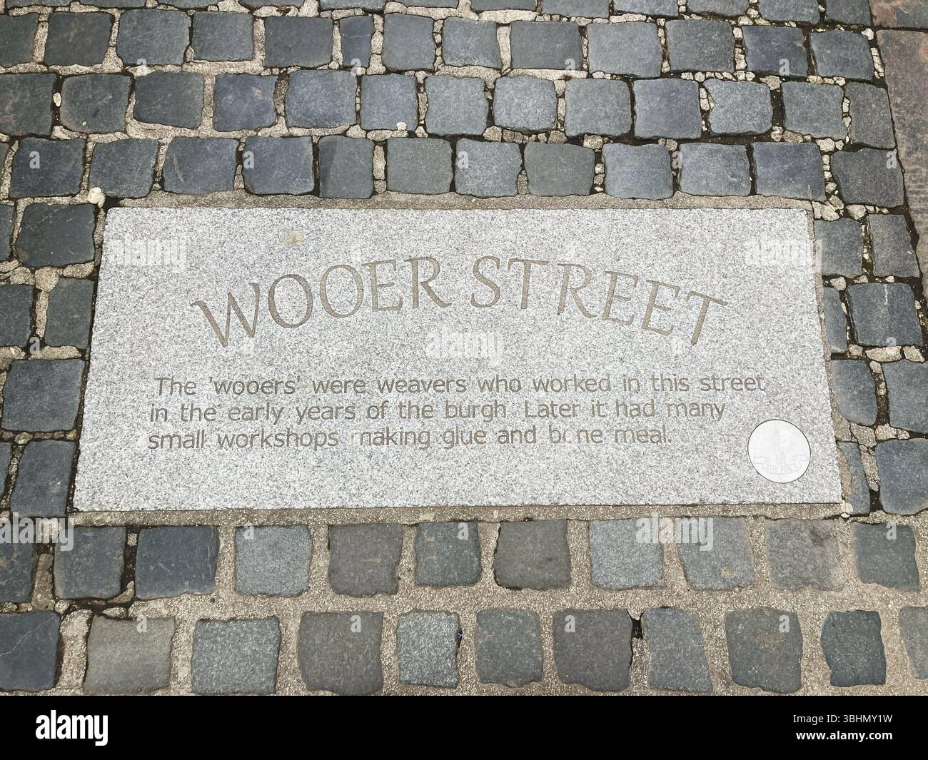 Inscription on the pavement with public information regarding Wooer Street, Falkirk Scotland - Smartphone Captured Stock Image