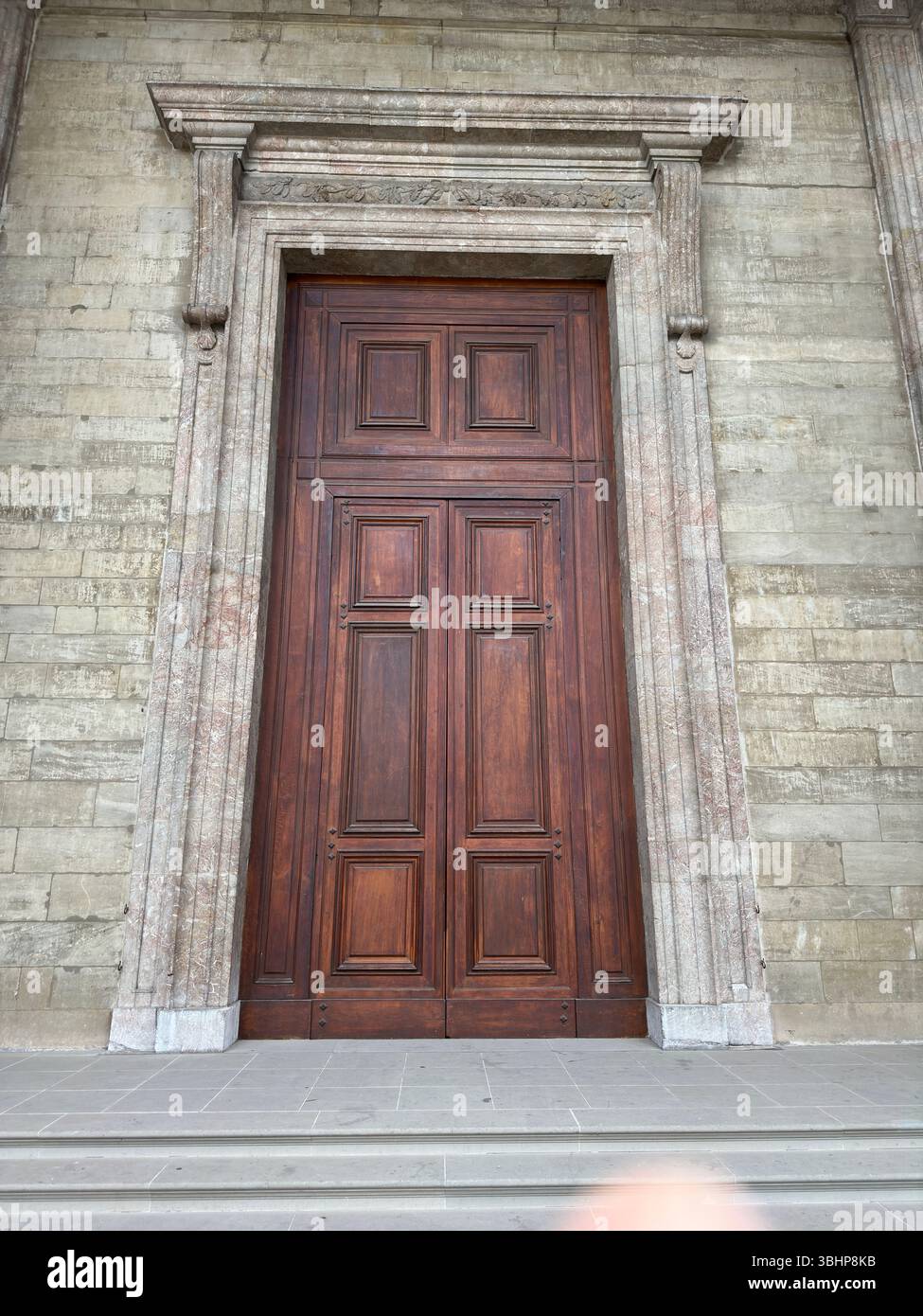 An impressive wooden door with an elegant stone framework. - Smartphone Captured Stock Image