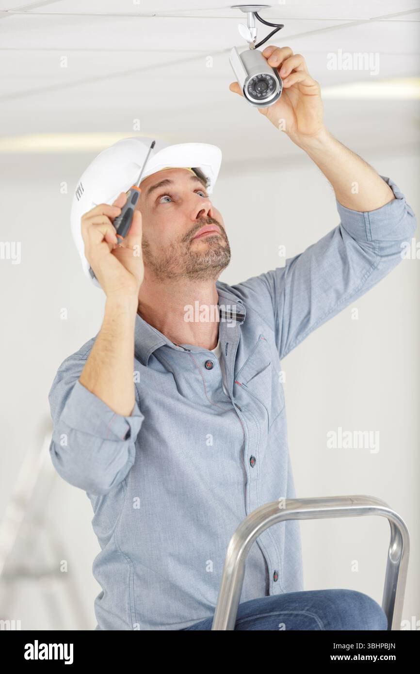 man installs surveillance ip camera for home security Stock Photo