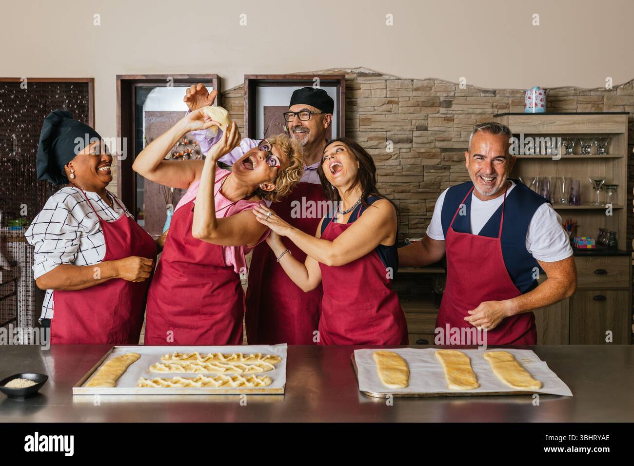 Cheerful chefs kneading dough and having fun in cooking class Stock Photo