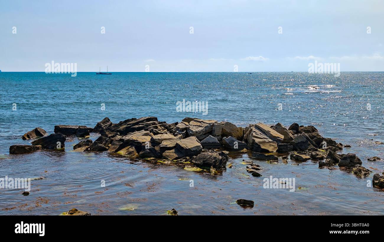 Rock formations emerging from the sea with ships visible on the distant ...