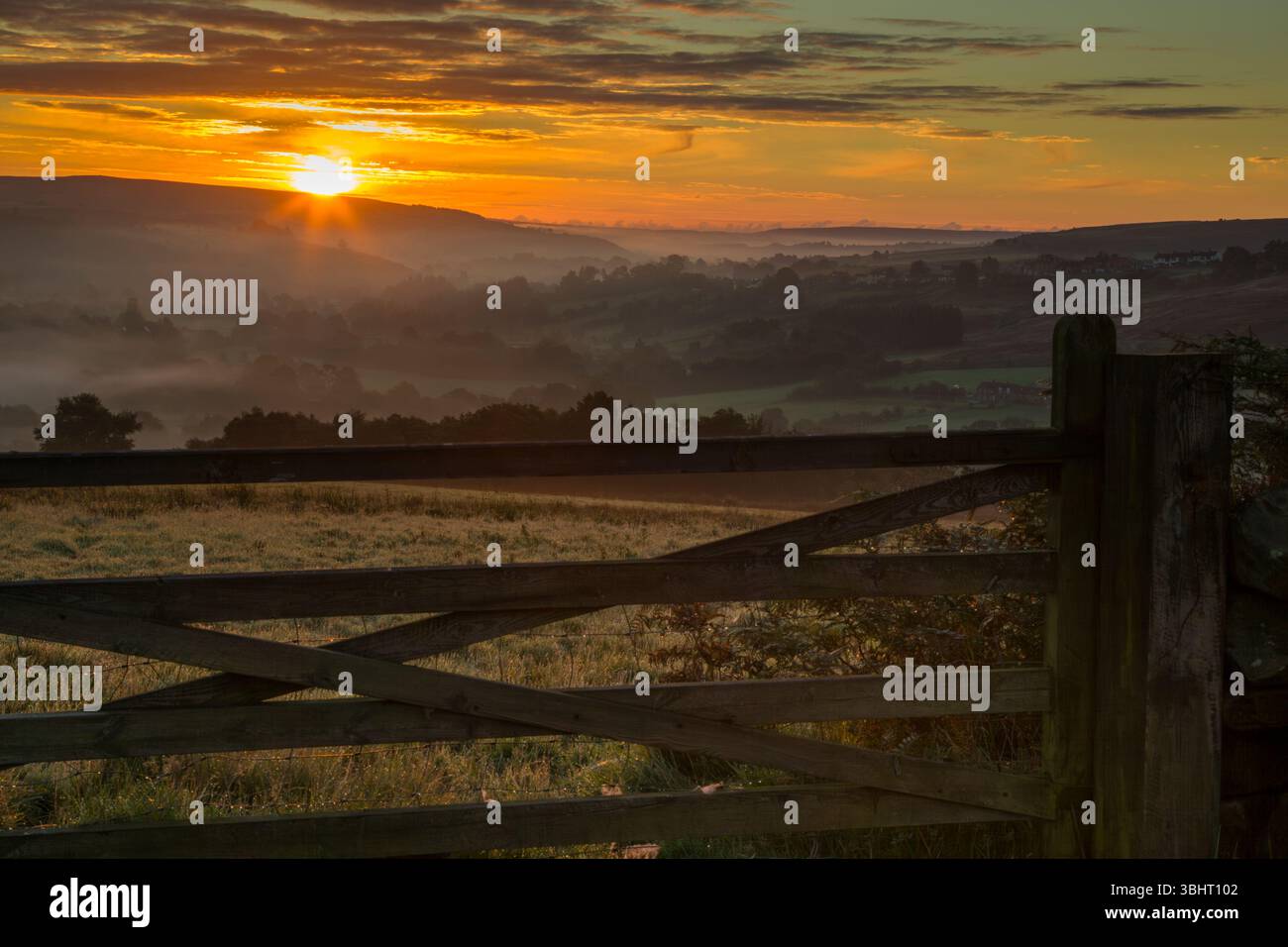 Early autumn sunrise view looking east towards Castleton Village and beyond along the mist filled valley of the River Esk - Stock Image