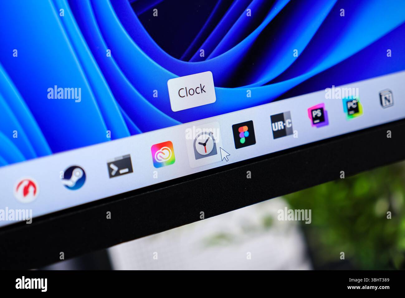 Poznan, Poland - June 6, 2025: Close-up of a computer display showing the taskbar with a mouse pointer activating the Clock app, emphasizing modern so Stock Photo