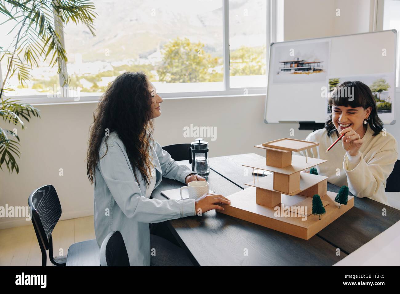 Two women engage in a creative planning session, discussing an architecture project with enthusiasm and focus. Stock Photo