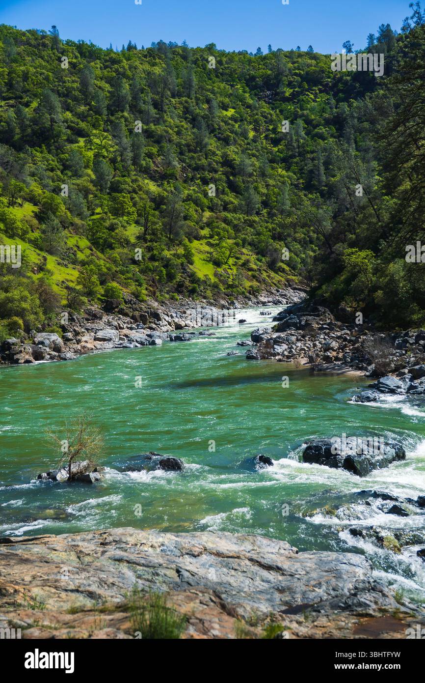 A scenic California river flows gently past rocky banks, surrounded by ...