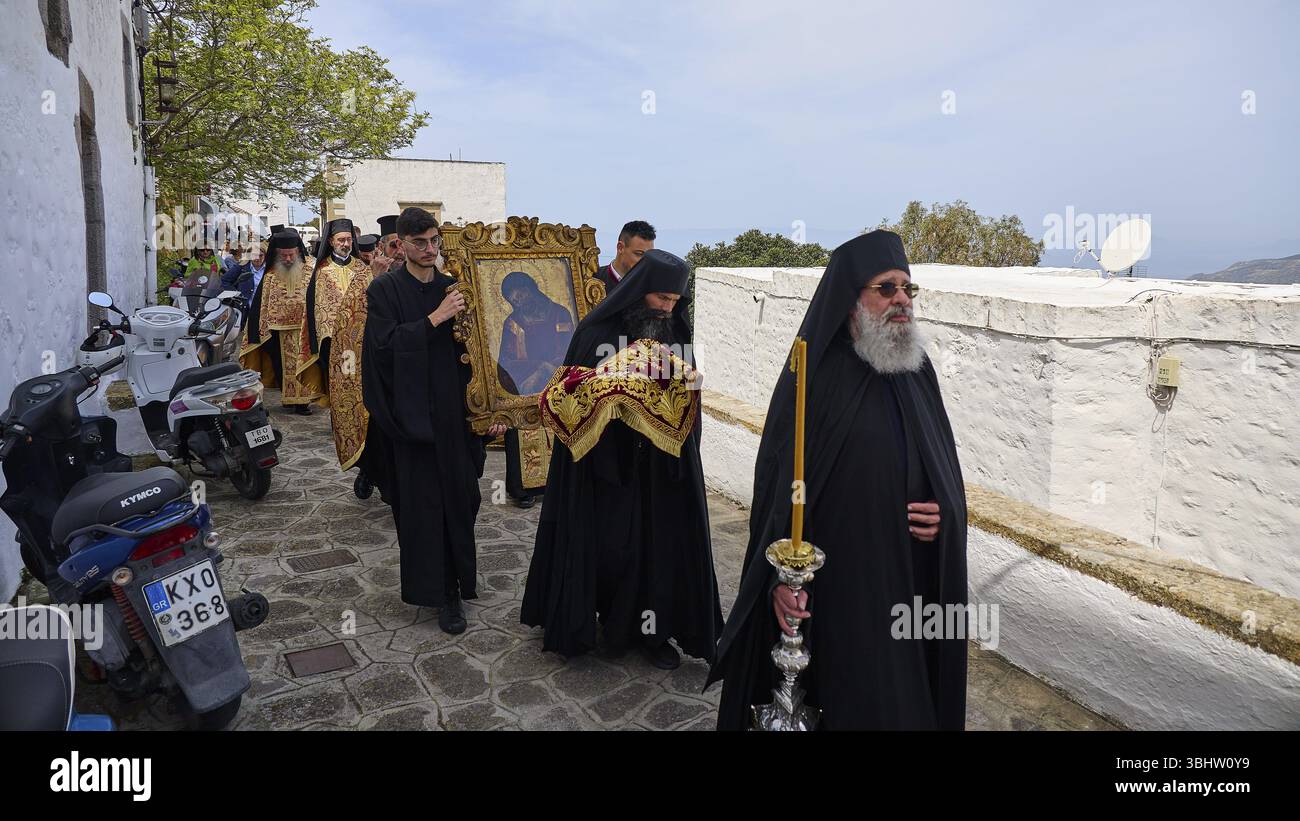 Priests in black robes and icon bearers walk along a wall during a ...