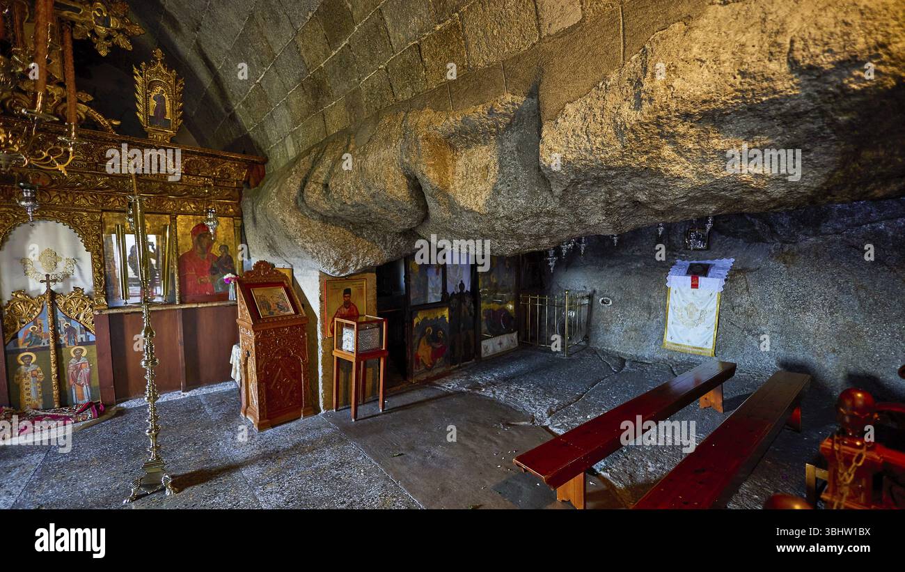 Church interior with icons and wooden benches set into a stone wall ...