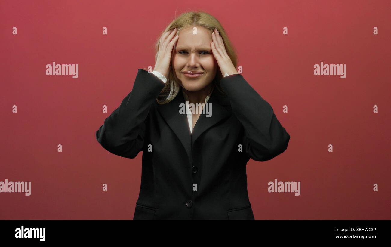 Woman with blonde hair looks distressed in front of a vibrant red ...