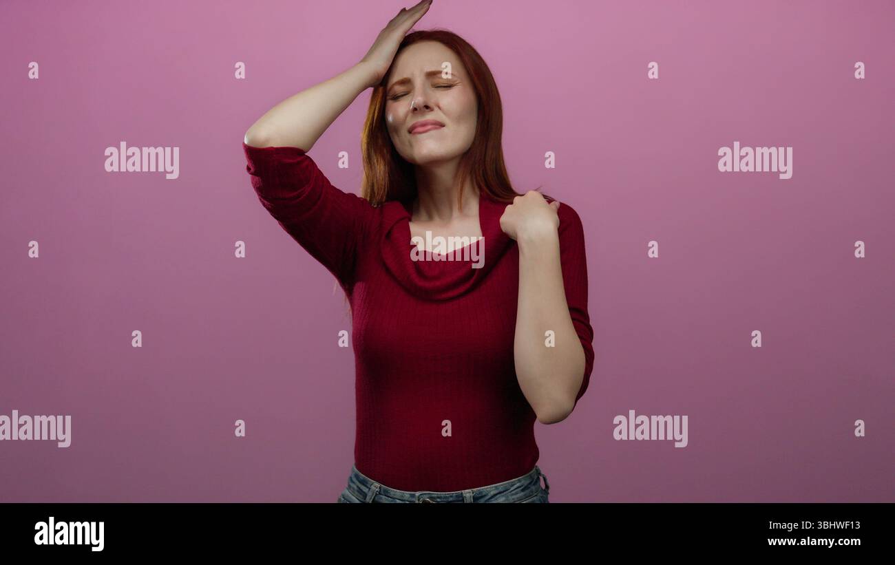 Woman expressing emotions wearing red sweater against pink background in isolated setting, showcasing expressive gestures and vibrant hair. Stock Photo