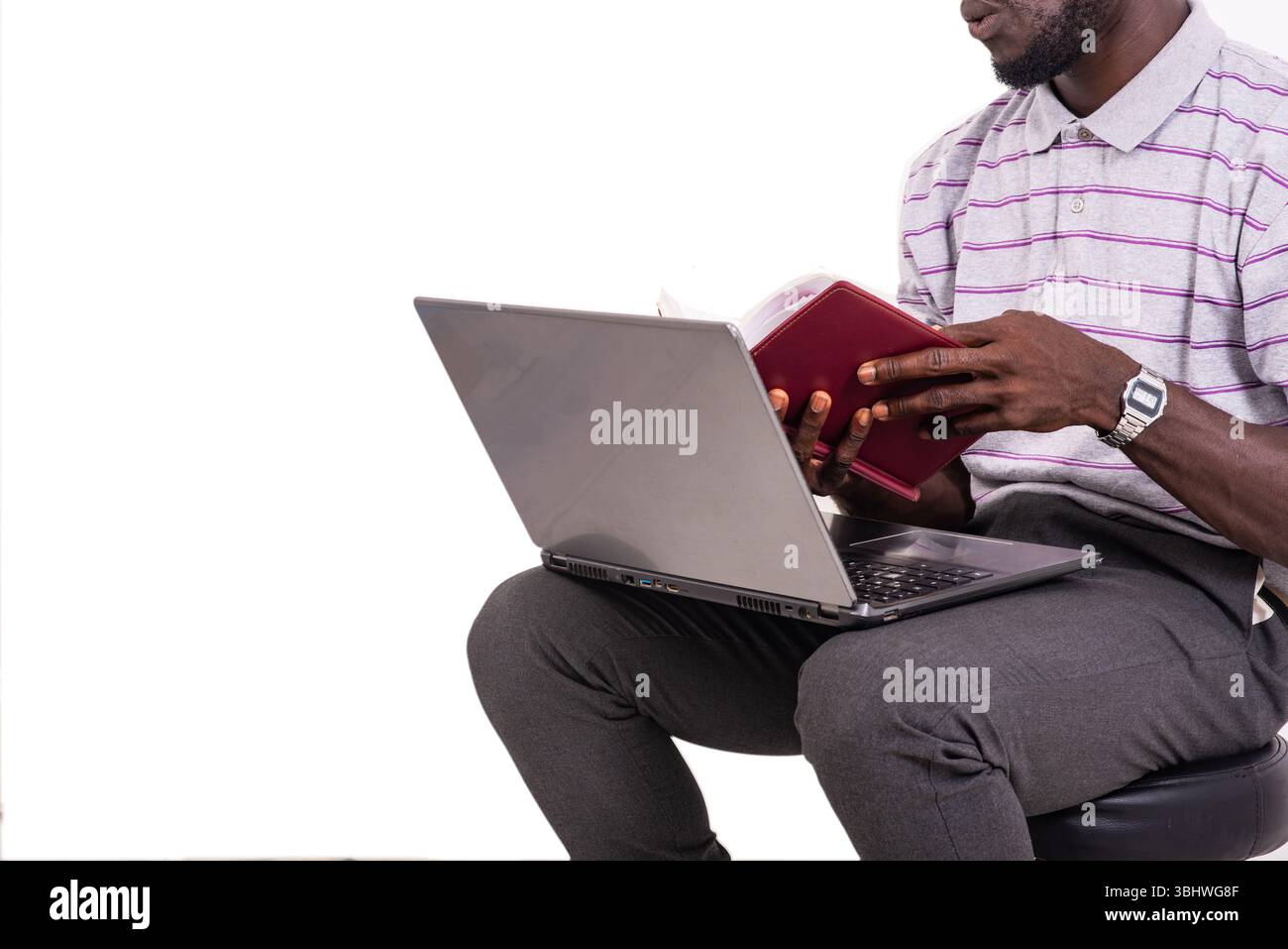 young man sitting on chair and checking notes in notebook using laptop. Stock Photo