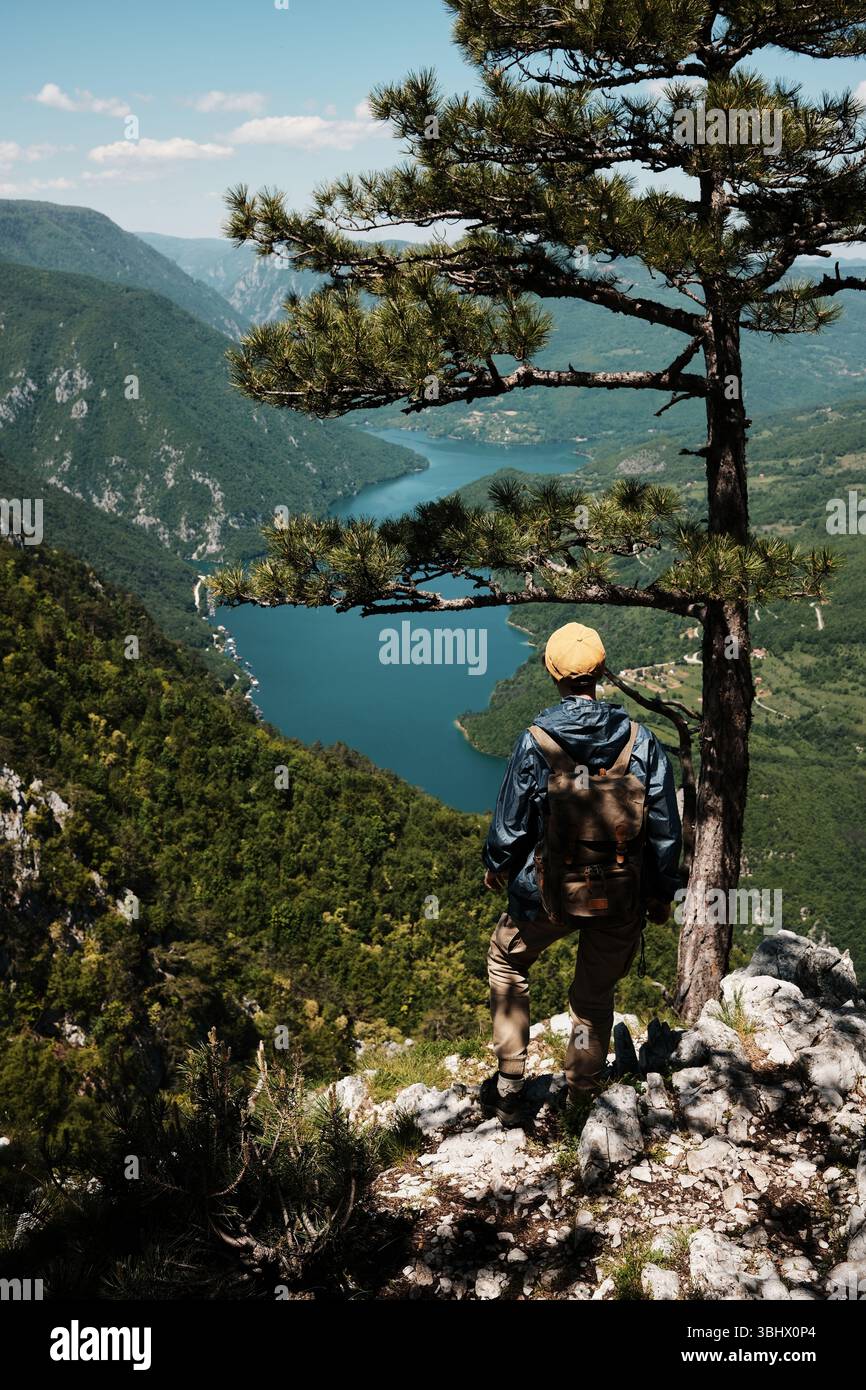 Lone female hiker with retro backpack standing on the cliff edge of ...