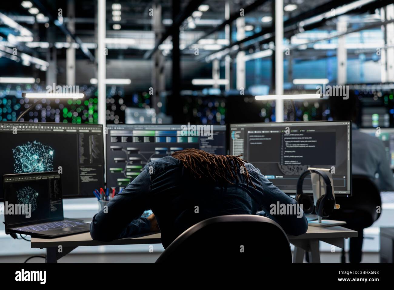 Exhausted server farm engineer falls asleep while using AI algorithms to analyze large datasets. Tired data center worker exhausted after using deep learning to recognize patterns in facility data Stock Photo