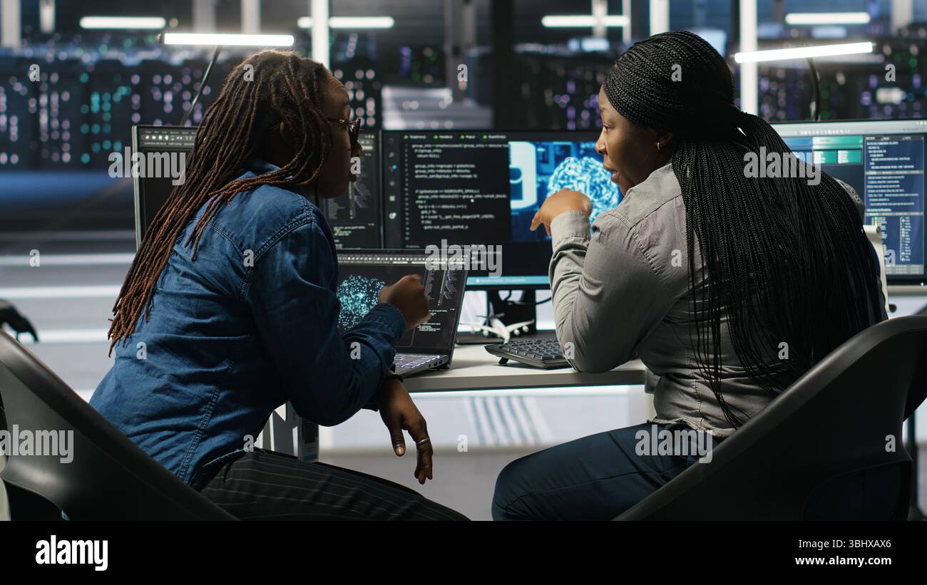 Data center coworkers doing brainstorming, using artificial intelligence machine learning models to configure equipment. IT experts cooperating in server farm, working on optimizing systems, camera B Stock Photo
