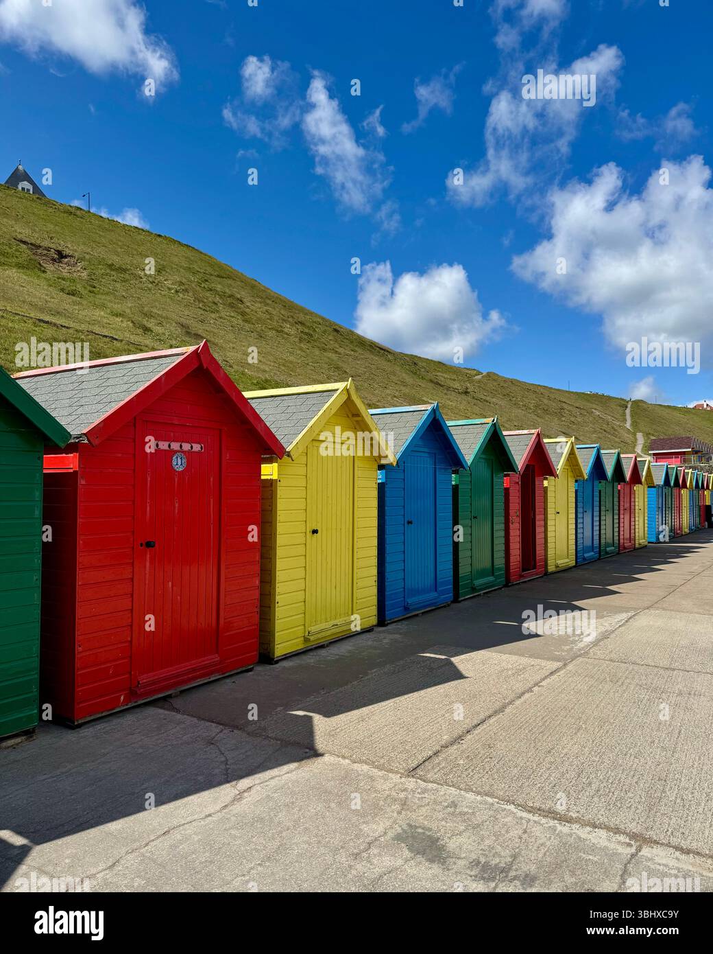 Colourful beach huts against hillside, on the coast at Whitby, Yorkshire, England - Smartphone Captured Stock Image