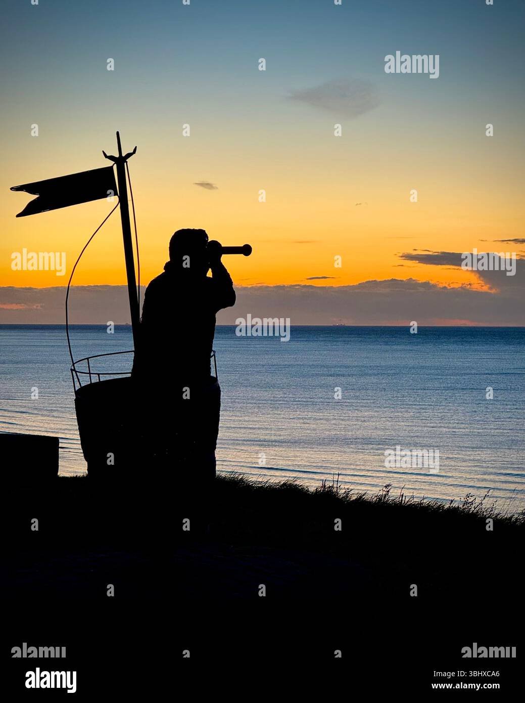 Statue of sailor looking out at sunset over North Sea at Whitby, Yorkshire, England - Smartphone Captured Stock Image