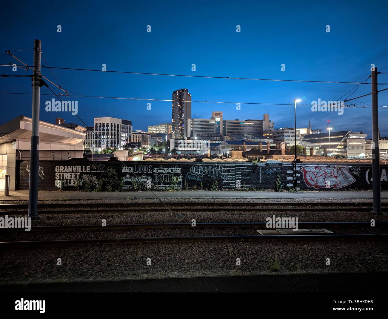 Night falls over Sheffield, England, UK, illuminating the Arts Tower and city lights, trams station, reflecting the vibrant urban glow of modern life. - Smartphone Captured Stock Image