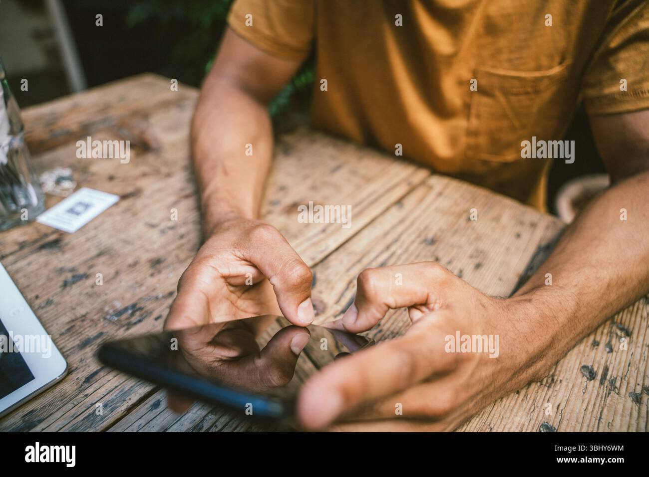 Closeup of man using smartphone while sitting at table in coffee shop Stock Photo