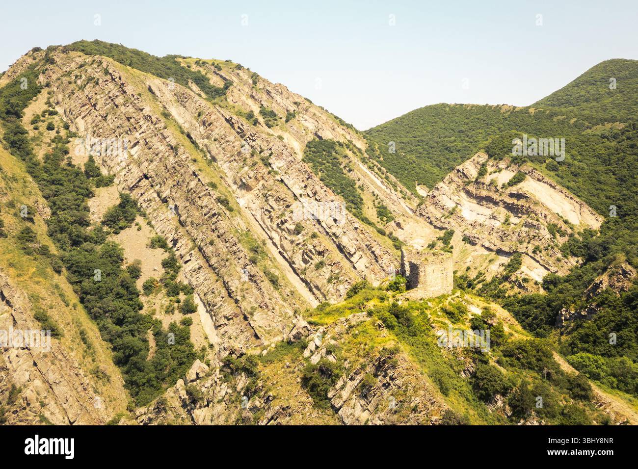 Aerial view of Armazi Fortress ruins on steep ridge with tilted rock ...