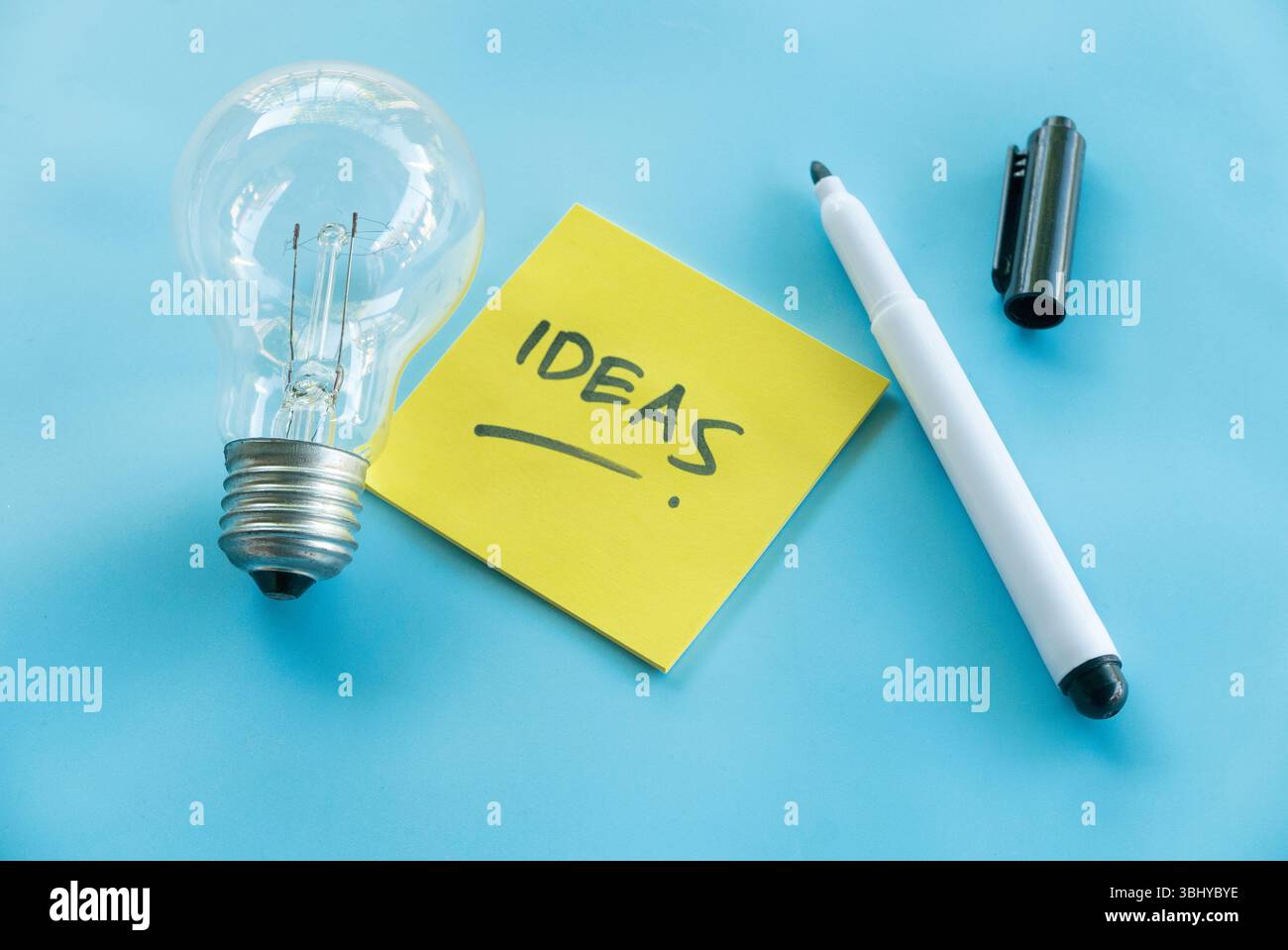Creative Ideas Concept with Light Bulb, Sticky Note, and Pen on Blue Background Stock Photo