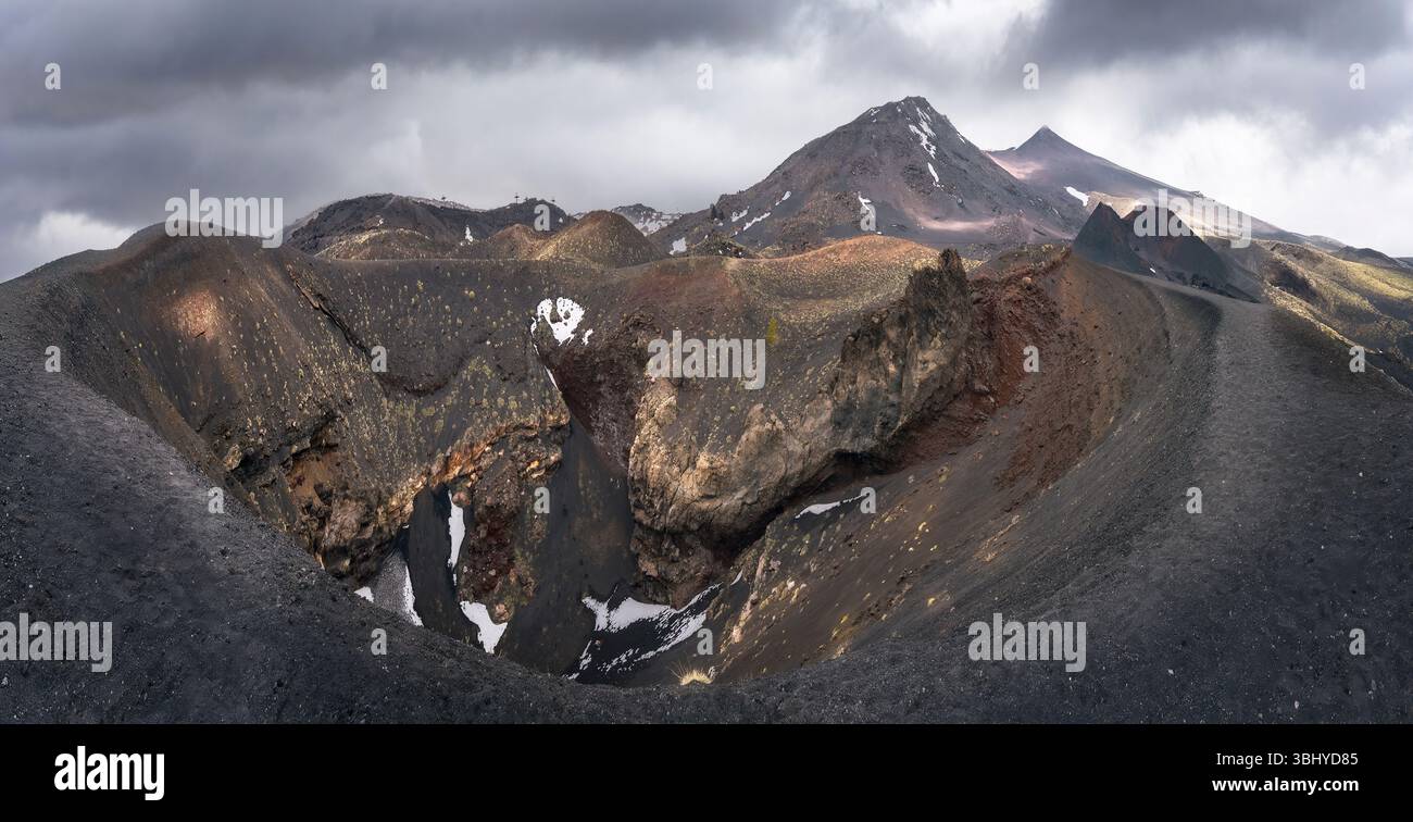 Majestic volcanic craters and rugged terrain fill the frame under a dramatic sky, inviting adventure in Etna Park, Sicily, Italy Stock Photo